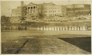 Navy ROTC members march down the field beneath the construction site of Stalnaker Hall.