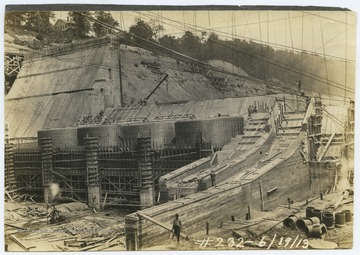 Men work around the site, conducting various tasks to build the dam. 