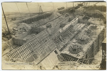 View overlooking the construction site of the dam, which is scattered with equipment and building supplies. 