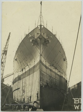 A crew works on the battleship in the dock area. 