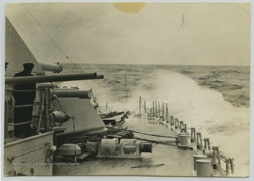 Crew members look out to the sea from the deck. 