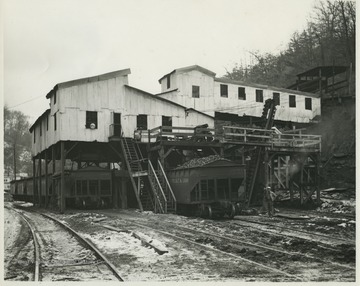 A coal miner stands beside the snow covered tracks where a C. & O. Railway car sits, filled with coal.  The mine is in Cameo, Boone County, W. Va.