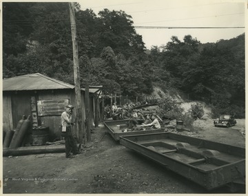 Miners light up cigarettes and sit on rail cars. Subjects unidentified. 