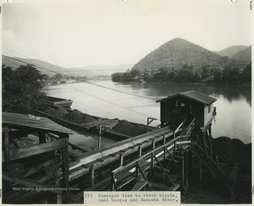 Filled coal carts belong to the Cedar Grove Collieries Inc. & Supply Co. sit in a line on the barges beside the river.