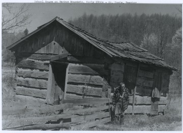 Mr. Ennis, the school teacher, stands outside of the old school building. The photograph was taken in the early 1900's. 