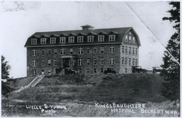 Cars are parked in front of the large stone building. The hospital was later renamed Raleigh General.