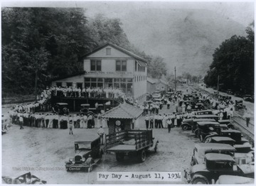 Workers line up around the building waiting to receive their paychecks. 