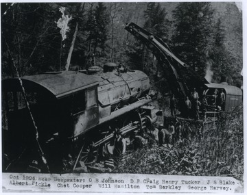 The train was carrying lumber from Robson, W. Va. to a C. & O. station at Deepwater, W. Va before wrecking. Pictured are O. B. Johnson, D. P. Craig, Henry Tucker, J. S. Blake, Albert Pickle, Chet Cooper, Will Hamilton, Tom Berkley, and George Harvey. 