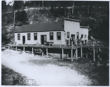 Photograph from the early 1900's, showing a group of men that are standing on the saloon porch.