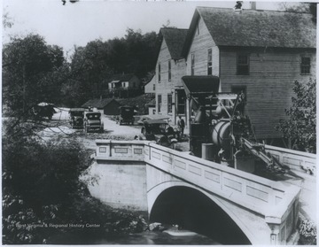 A large machine paves the roadway of the bridge.