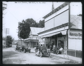 Men and women sit outside store entrances on benches and in parked automobiles. Subjects unidentified. 