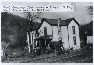 Beside the building and the railroad is a mail crane. 