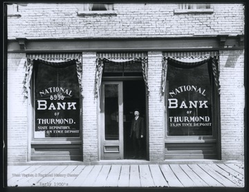 An unidentified man stands at the building's entrance. 