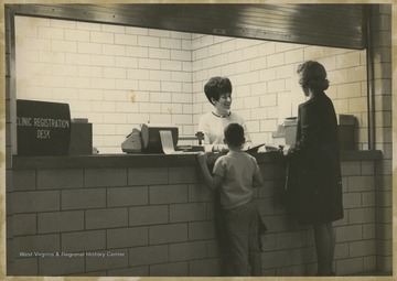 A mother and her child are greeted by a secretary at the WVU Medical Center.