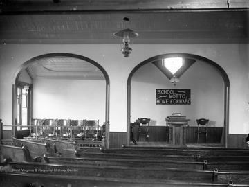 A sign hanging on the back wall reads, "School motto; 'Move forward,'" indicating that the church also serves as a school. 