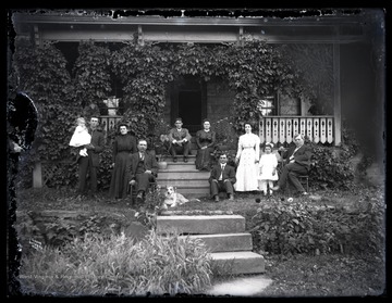 Family members and a pet dog sit outside of the home.