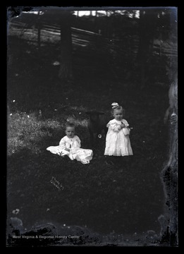 A child holds on to a glass baby bottle while posing for a picture. 