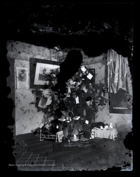 A decorated Christmas tree stands in the corner of the house with presents sorted beneath it.  The home likely belongs to Orvis Zacheus "Oz" Gibson, a brother of the photographer, Scott Gibson.