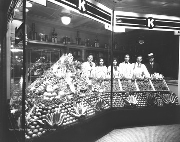 Employees of the Kroger stand behind a stand of fruits and vegetables. 