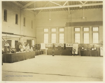 Three professors stand behind a display booth on the left while a student poses beside a large display on the right. Subjects unidentified. 