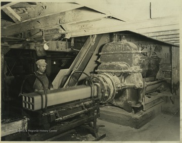 An unidentified worker supervises as the machine molds concrete into support beam structures. 