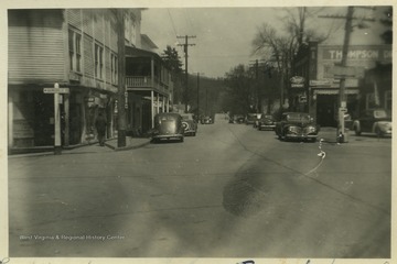 Cars line the street of the downtown area. On the right is Thompson Drug Co.