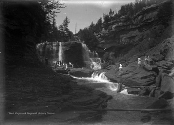 People climb the rocks of Blackwater Falls as they observe the gushing waterfalls. 