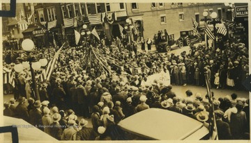 Parade participants with what appears to be a May Day pole march down High Street.