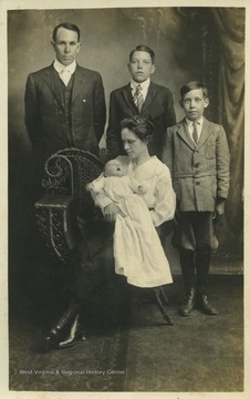 Mr. Nutter (left), Earl Parker (center) and Fred Nutter (right) stand in the background while Mrs. Nutter (front) holds the Nutter baby. 