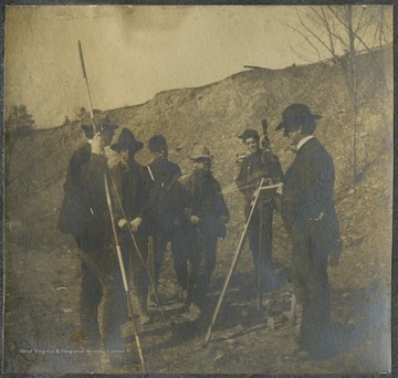 A group of unidentified men listen to another explain the Searles Spiral during the surveying for the Baltimore and Ohio Railroad.This photograph is found in a scrapbook documenting the survey for the B. & O. Railroad in West Virginia and surrounding states. 