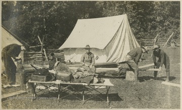 A group of men are pictured performing various tasks. The men are identified, from left to right, as "Coe"; "Sandy"; "Rat"; "Dobbie"; and Heinie Miller.This photograph is found in a scrapbook documenting the survey for the Baltimore and Ohio Railroad in West Virginia and surrounding states. 