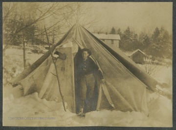 Summerville makes his way out of a tent and into the snow.This photograph is found in a scrapbook documenting the survey for the Baltimore and Ohio Railroad in West Virginia and surrounding states. 