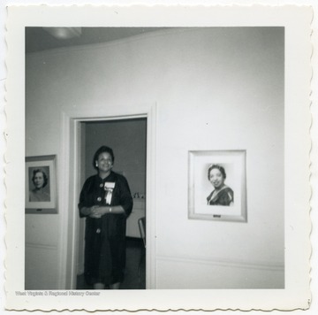 Carey B. Preston standing next to a photo of herself in the Alpha Kappa Alpha Sorority National Office.