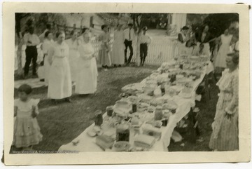 Picnic table visible, laden with food.