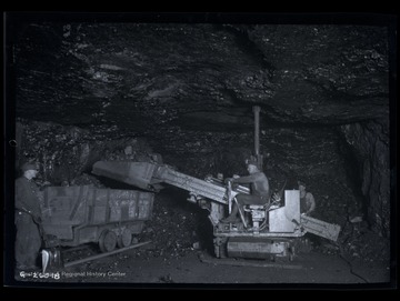 Three men working to fill a coal car.