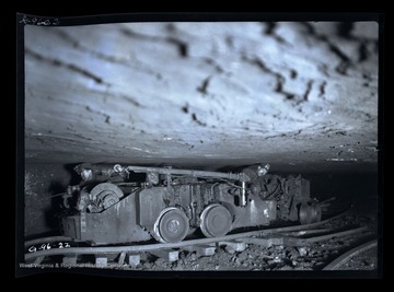 Two men travel through a narrow passageway in mine.