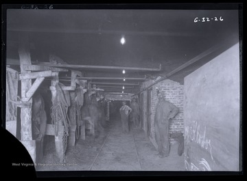 Three men pose for photo inside a mining stable, likely located underground.