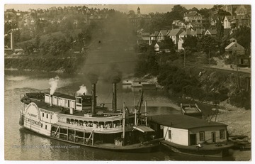 The "I. C. Woodward," launched in 1898 for the Pittsburgh, Brownsville, and Geneva Packet Company, and traveled between Pittsburgh and Morgantown. Woodburn Hall and Martin Hall can be seen on the bank in the background.