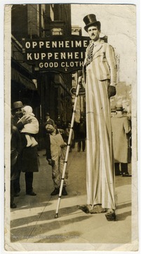 "Charlie Chaplin's double on 4 hour stiltwalking ... period. The sidewalks, also indoors and outside stilting." Long poses outside Oppenheimer's Kuppenheimer Good Cloth store on High Street.