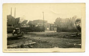 Train passes in front of storefront with sign that reads "Crotty and Company."