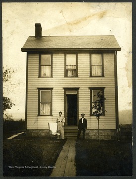 A man and a woman stand outside the front door of their home near Cheat Lake.