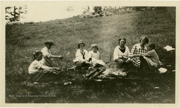 Members cooking bacon for lunch over campfire.