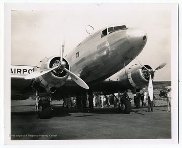 People gather around an aircraft for a ceremony for the opening of an airline at Harrison County Airport, now called Benedum Airport. 