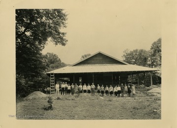 Group of 4-H members pose in front of cottage as late stages of construction are completed.