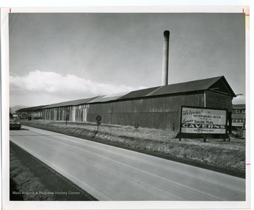 Welcome sign advertising the "Famous Smoke Hole Caverns" in Petersburg, West Virginia.  Petersburg tannery building in background.