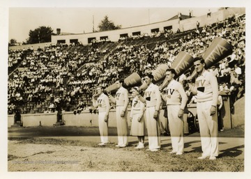 Four men and a young lady stand inside football stadium. 