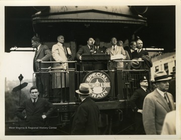 Roosevelt stands in background while being introduced to crowd.