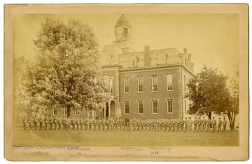 Three men are identified in this photo. Ninth from left is C. E. Charles, nineteenth from right is T. Stribling, and the Commandant L. Wilson stands in the center in the dark uniform.