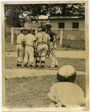 A Little League team and their coach discuss strategy on a Morgantown field. 